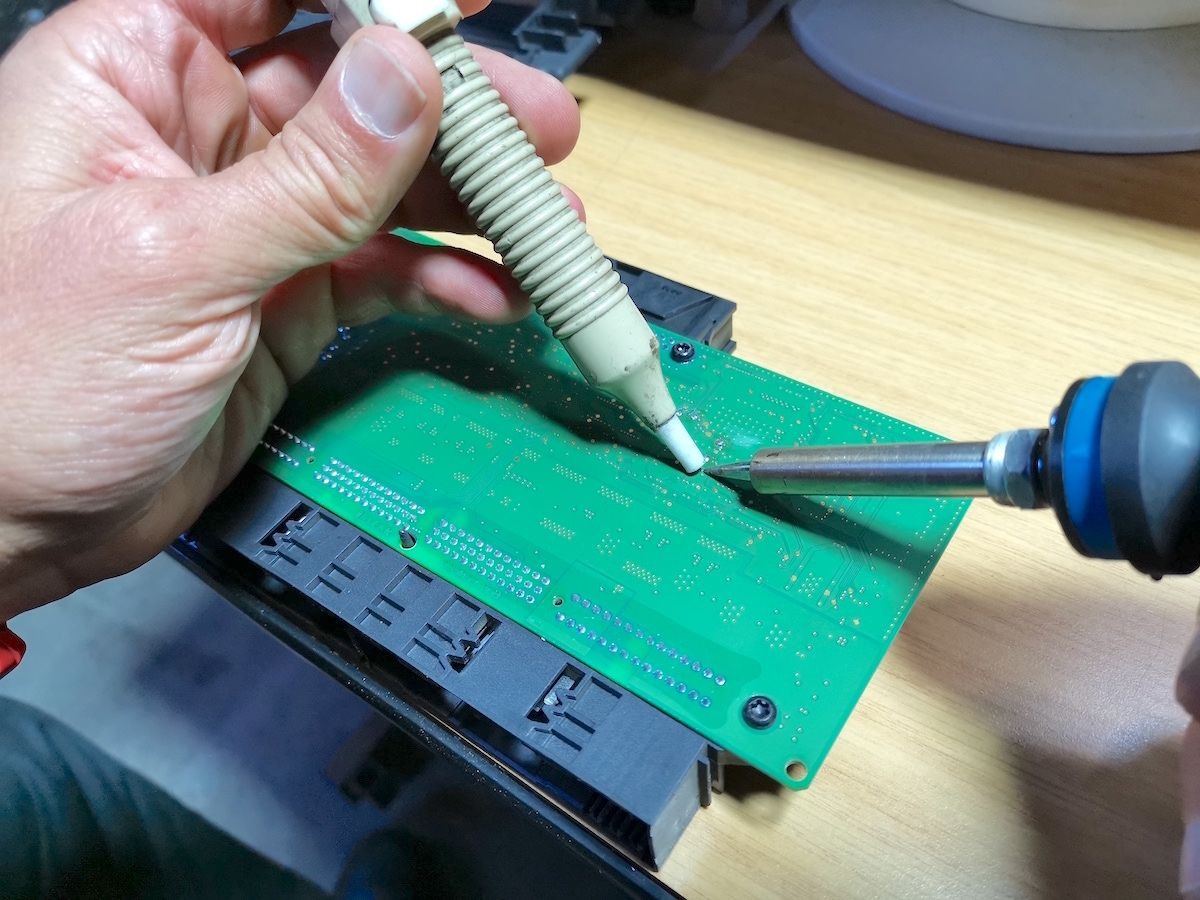 Board-level soldering work on a BMW footwell module during FRM repair